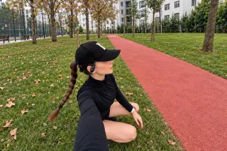 Corredora usando los audífonos Lenovo XT80 en un parque
